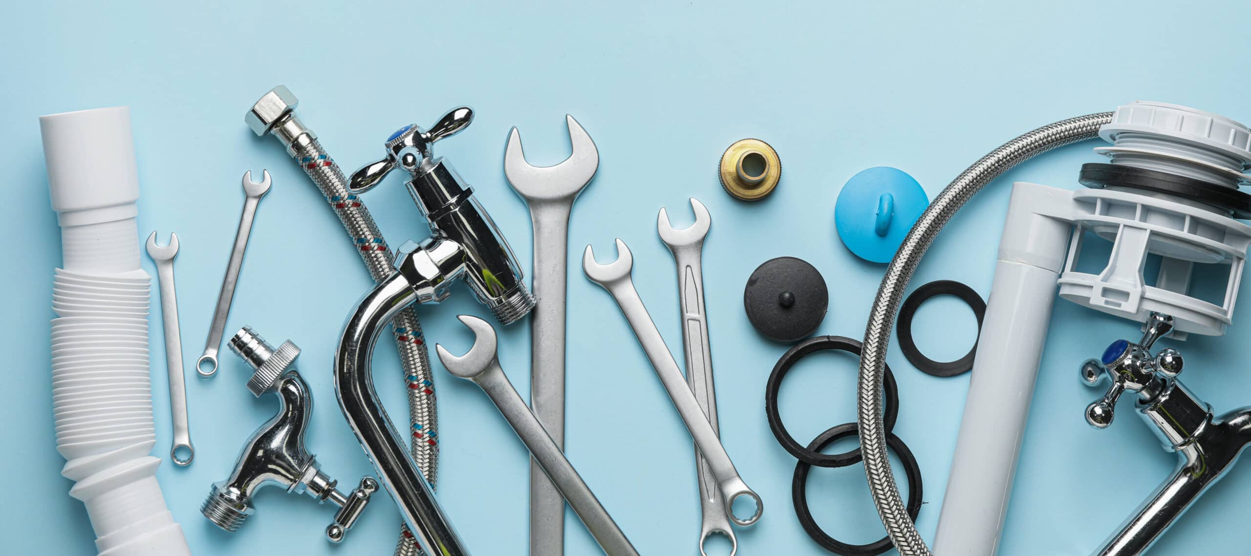 Assortiment d'outils et pièces de plomberie (clés, tuyaux, robinets, raccords, joints, flexibles) sur fond bleu clair.